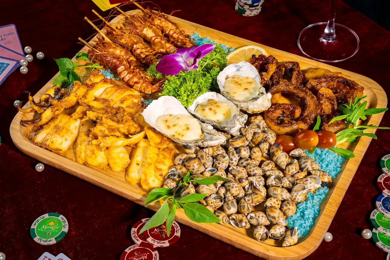 Mariscada gallega con almejas, ostras y gambas sobre tabla de madera